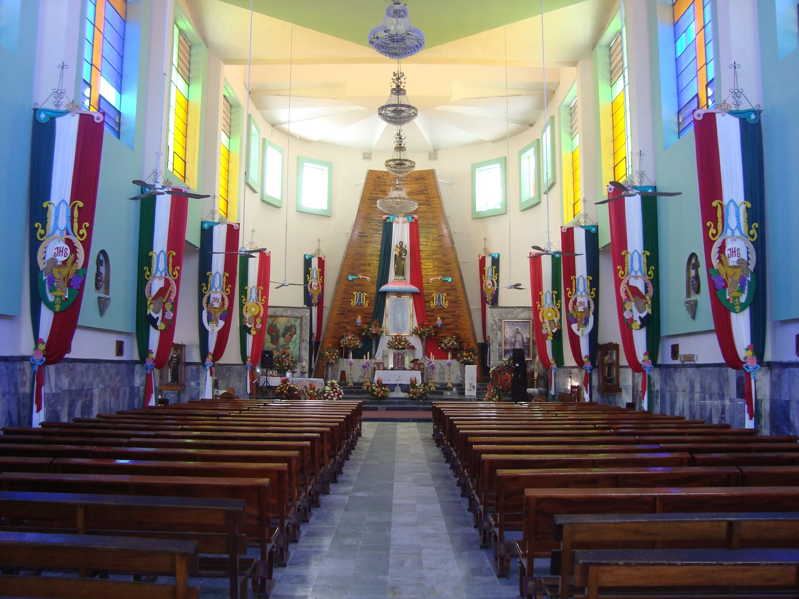 Intérieur de l’église San José à Casimiro Castillo, avec ses vitraux et ses bancs en bois